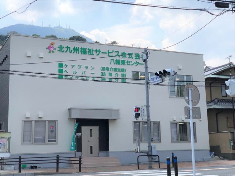 白い外壁に施設名看板がある介護施設の建物正面